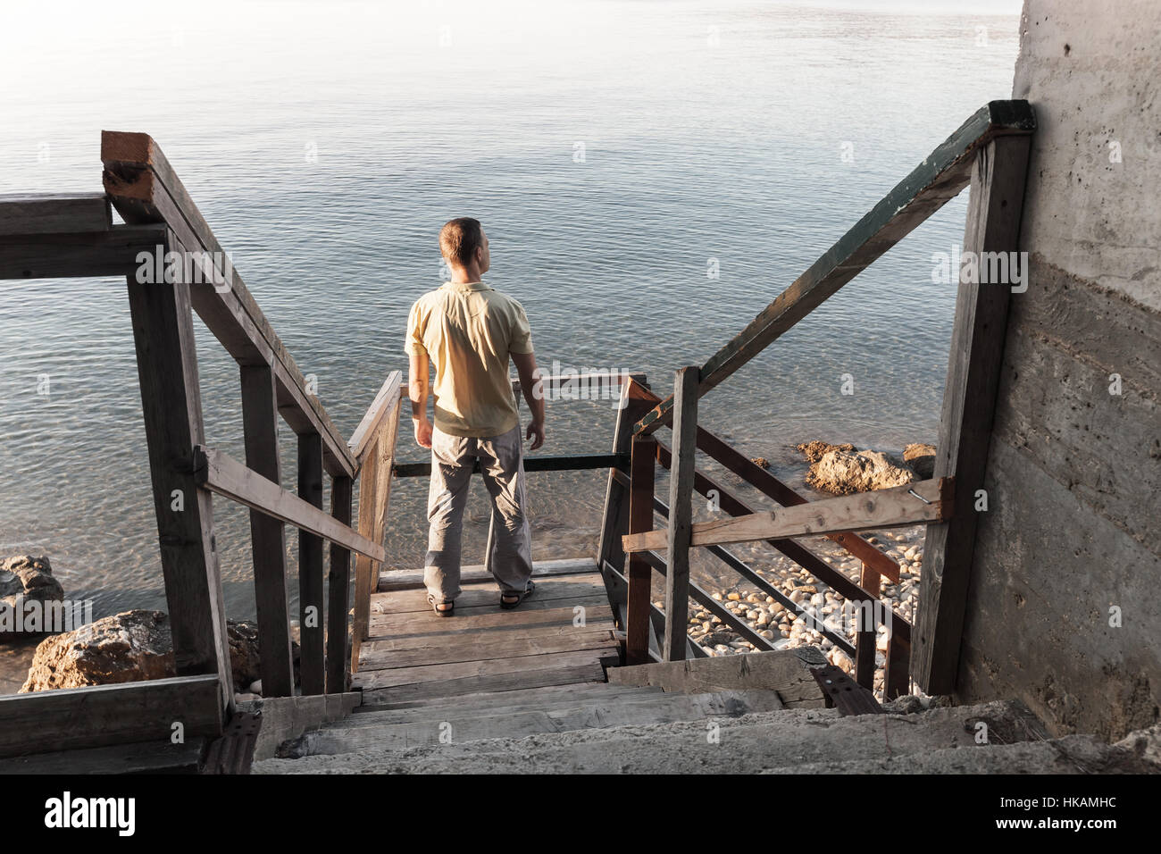 Jeune homme se dresse sur l'ancien escalier en bois qui descend jusqu'à la côte de la mer Banque D'Images