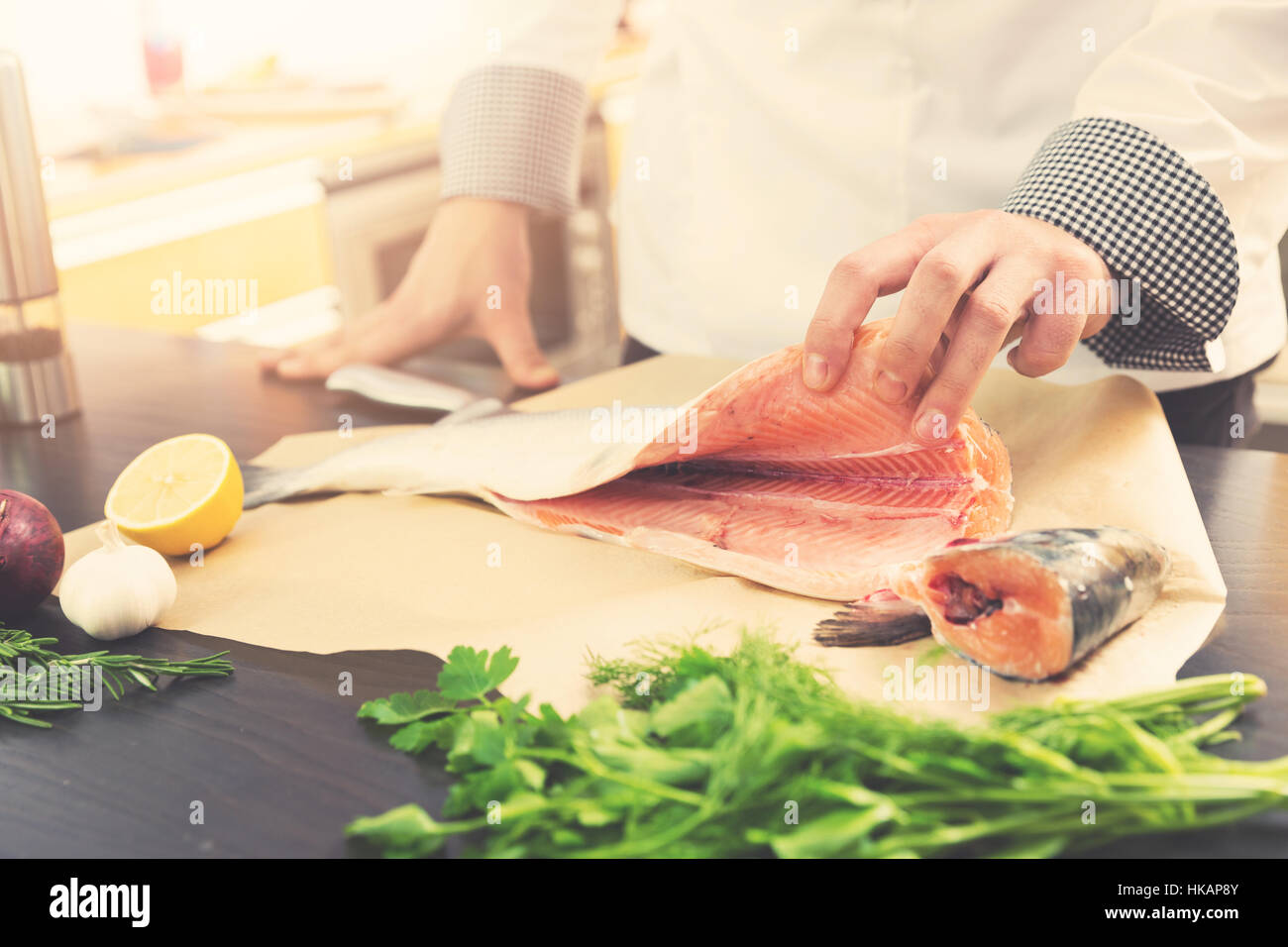 Chef prépare des saumons avec herbes et épices pour la cuisson dans la cuisine Banque D'Images