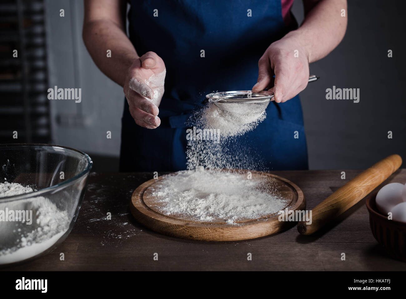 Baker sasser la farine dans la boulangerie, cropped shot Banque D'Images