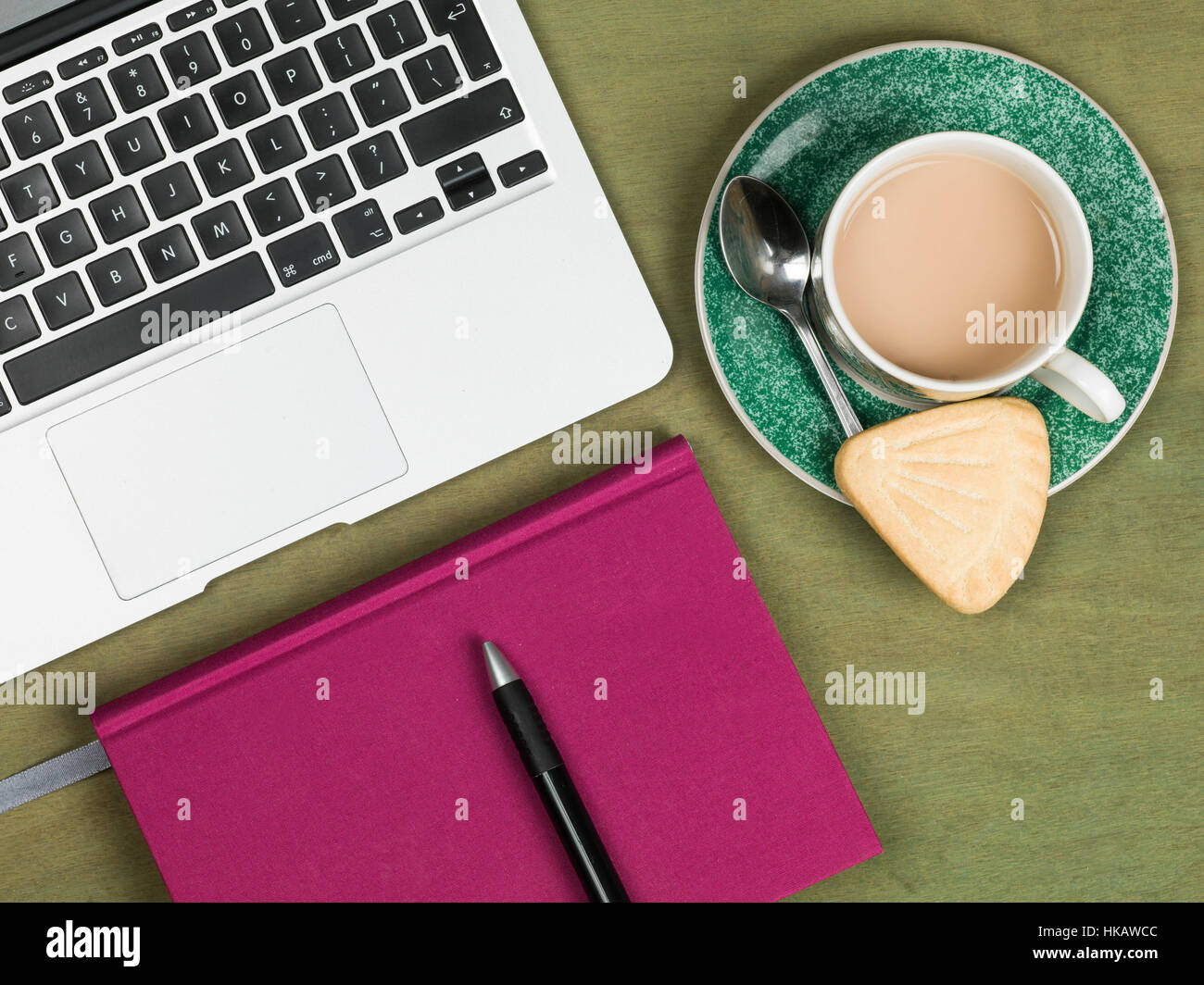 Une entreprise moderne ou créatif Workstation sur un bureau vert avec un ordinateur portable avec pas de personnes et d'un ordinateur portable et un plateau/bouilloire et d'une biscuiterie Banque D'Images