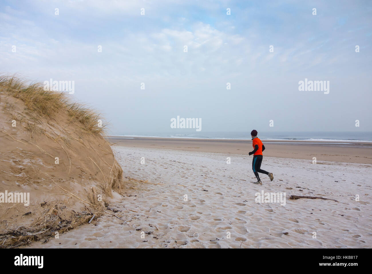 Homme mature qui court sur des dunes de sable couvertes de gel à Seaton Carew, sur la côte nord-est de l'Angleterre. ROYAUME-UNI Banque D'Images