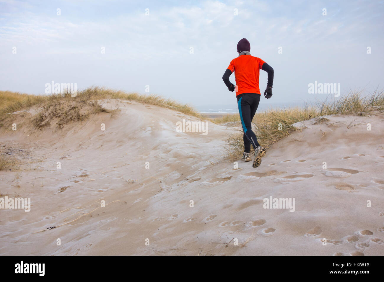 Homme mature qui court sur des dunes de sable couvertes de gel à Seaton Carew, sur la côte nord-est de l'Angleterre. ROYAUME-UNI Banque D'Images