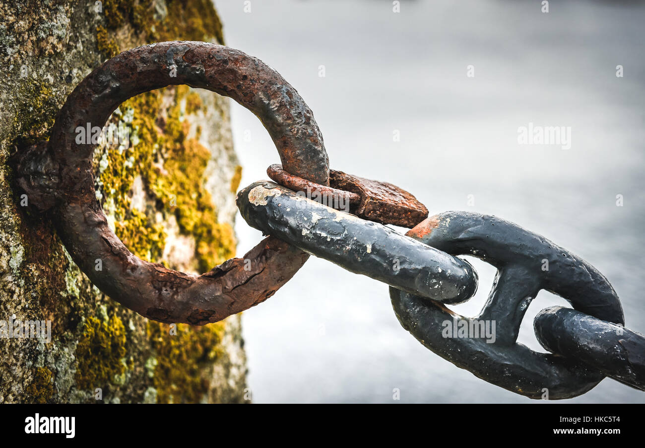 Old rusty anchor dans la chaîne de navire d'un port de mer. Vieille Clôture faite d'éléments obsolètes de la chaîne bateau mer océan avec en arrière-plan. Banque D'Images