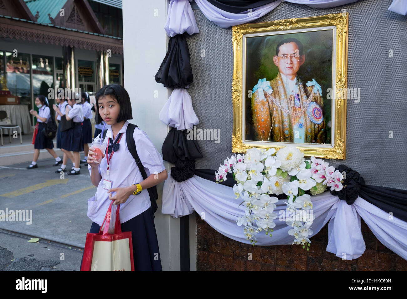Fille de l'école thaïlandaise est vu à côté d'un portrait du roi Bhumibol Adulyadej Banque D'Images