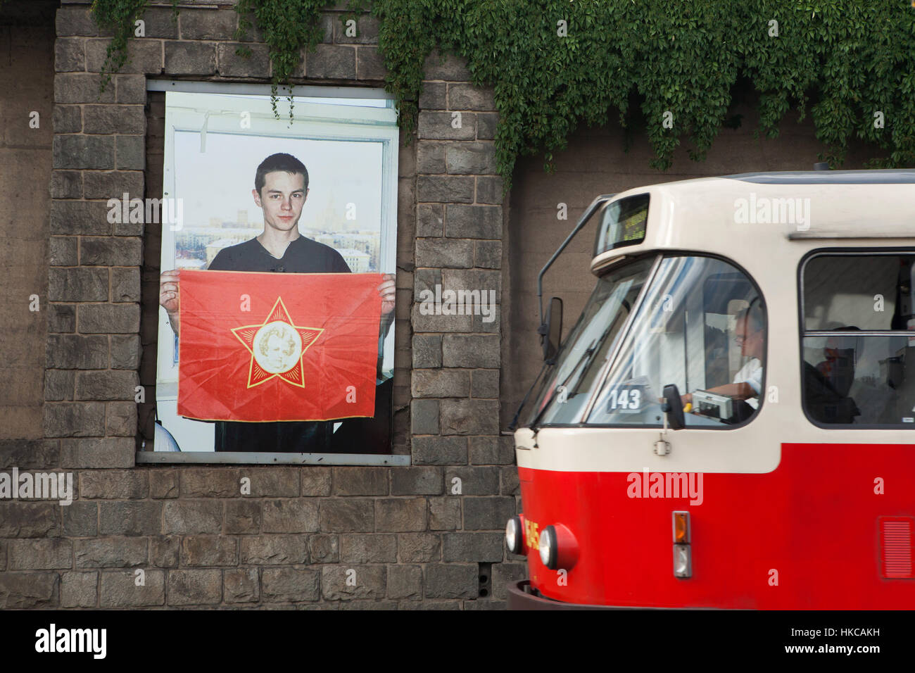 Le tram passe par la photographie par le photographe russe Slava Mogutin à partir de la série Lost Boys. From Russia with Love affichés à l'extérieur à son exposition à la galerie Artwall à Prague, République tchèque. Un garçon sur la photo est titulaire d'un drapeau rouge de l'organisation de la jeunesse soviétique peu Octobristes avec l'étoile à cinq branches d'un insigne avec le portrait de Vladimir Lénine dans son enfance. Banque D'Images