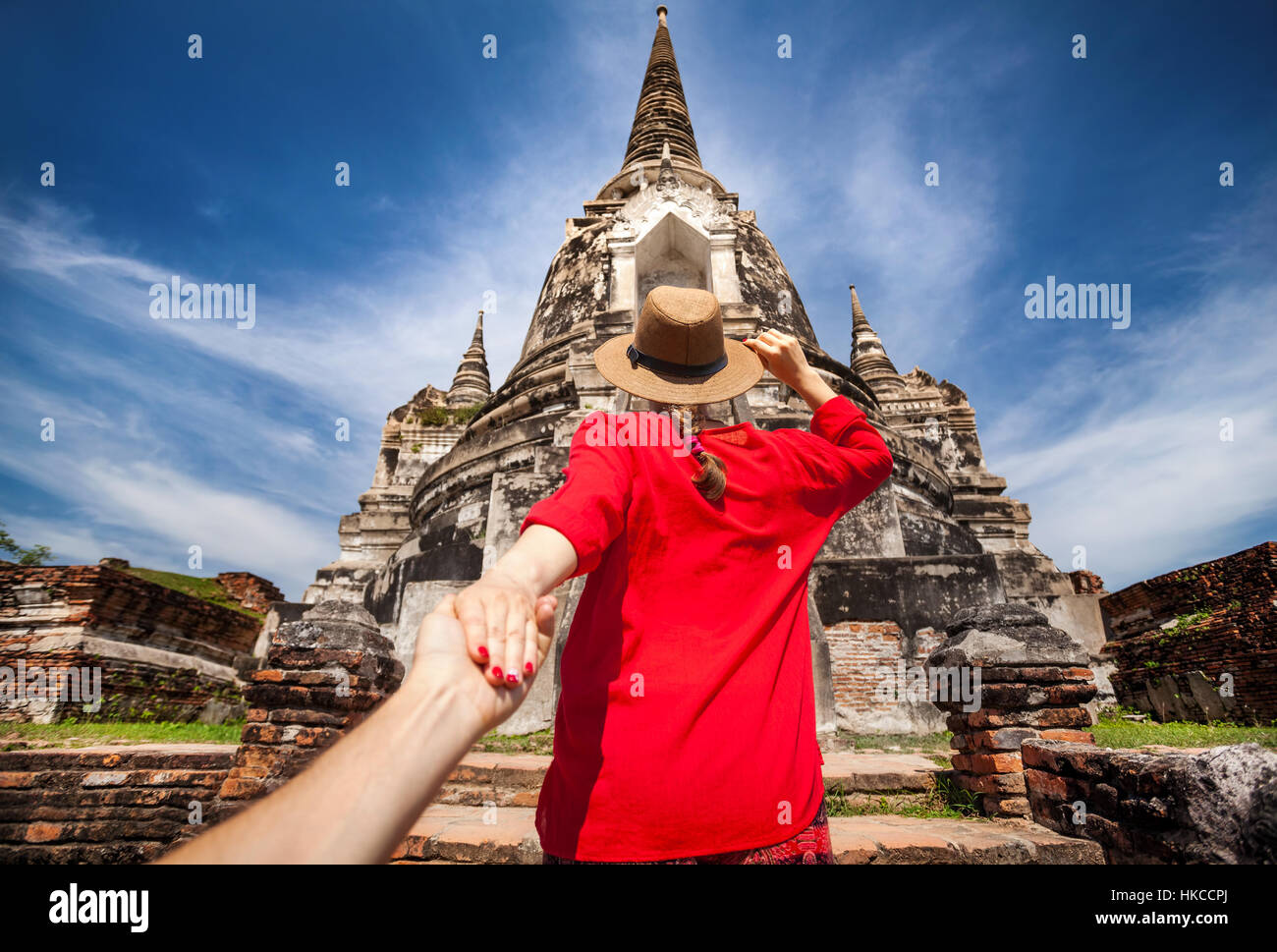 Woman in red shirt touristiques tenant son mari par la main et aller à l'ancien stupa dans le parc historique d'Ayutthaya, Thaïlande Banque D'Images
