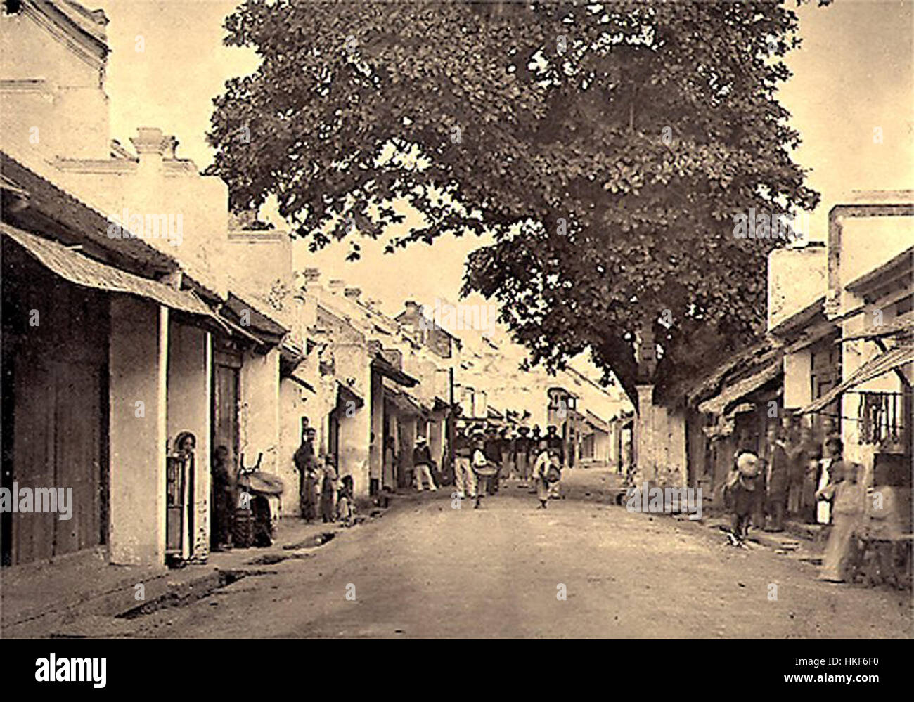 Hanoi Rue du change est une peinture à l'huile représentant une scène de rue à Hanoi, au Vietnam. La pièce capture la vie quotidienne et l'architecture historique de la région, en se concentrant sur l'activité animée de la région au début du XXe siècle, avec des bâtiments traditionnels vietnamiens et des gens en mouvement. Banque D'Images