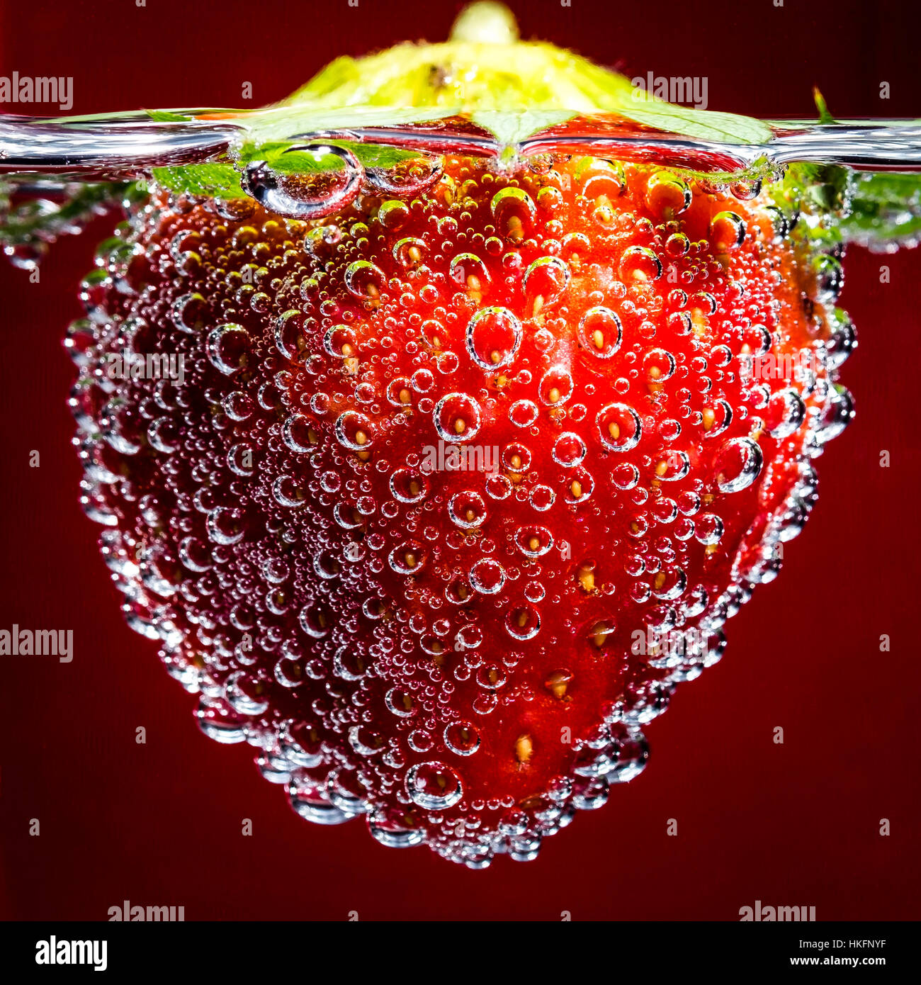 Fraise rouge flottant dans l'eau avec de minuscules bulles Banque D'Images