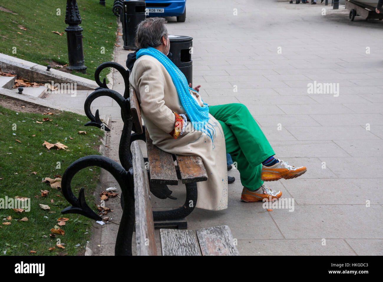 Un homme habillé de couleurs vives s'assit au bord du fleuve en Richmond upon Thames, Surrey Banque D'Images