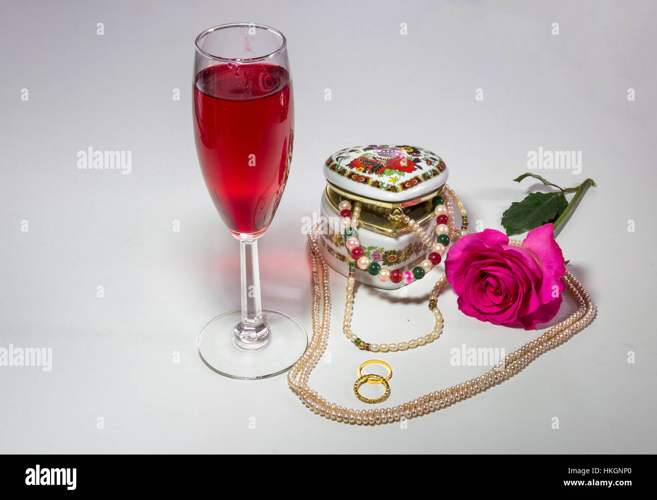 Contenu romantique en forme de coeur avec boîte de bijoux artistiques avec colliers de perles de verre de vin rouge rose rose et anneaux d'enclenchement. Banque D'Images