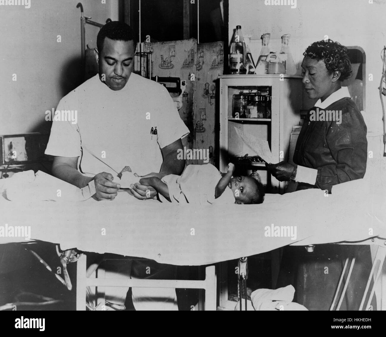 Un médecin américain africain non identifié, assisté par une infirmière, le traitement d'un bébé né avec un pied bot à une clinique de santé publique, 1945. À partir de la Bibliothèque publique de New York. Banque D'Images