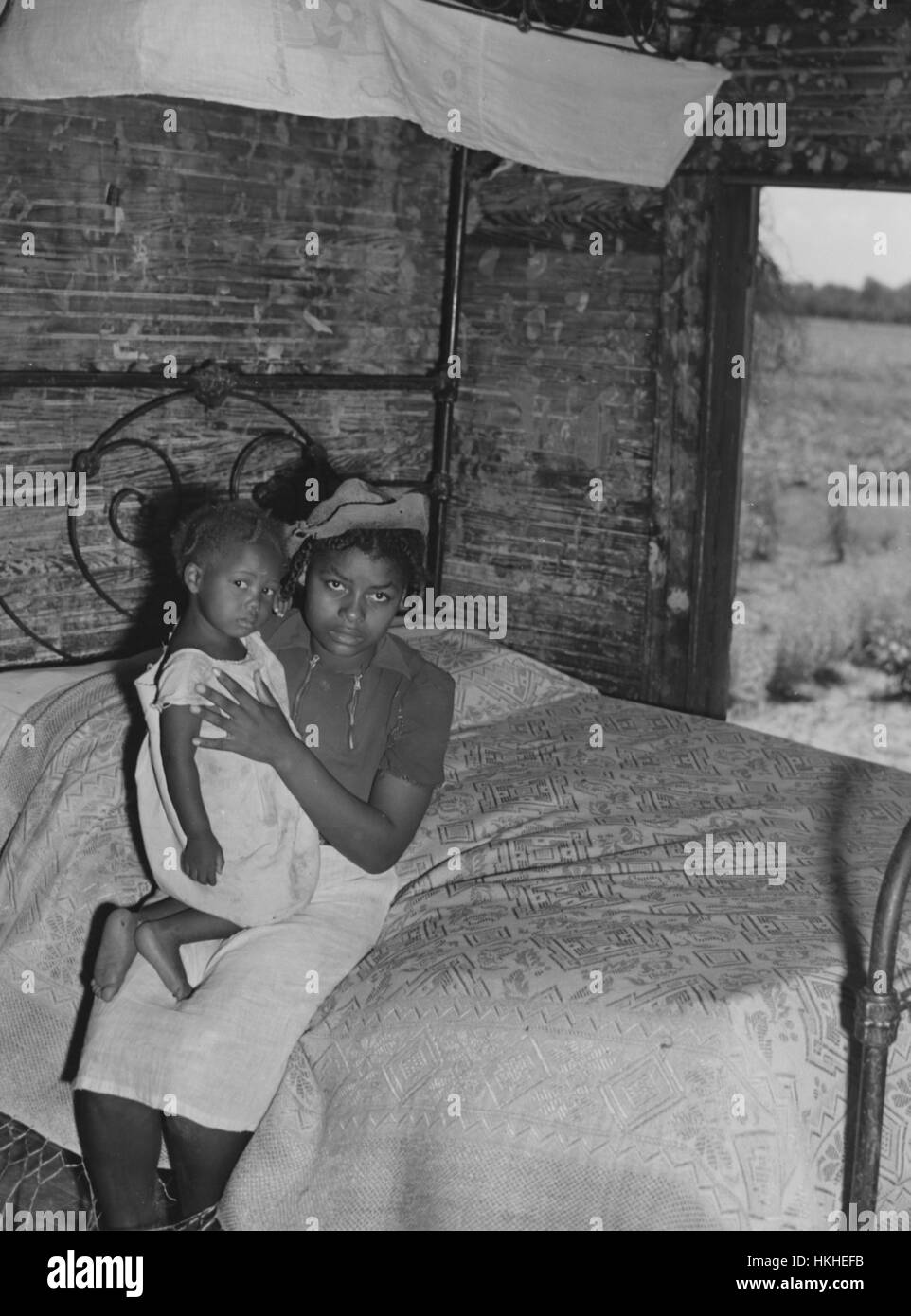 Une jeune femme est assise sur un lit tenant un enfant sur le Bayou Bourbeaux en plantation Natchitoches parois, Louisiane, Août, 1940. Banque D'Images