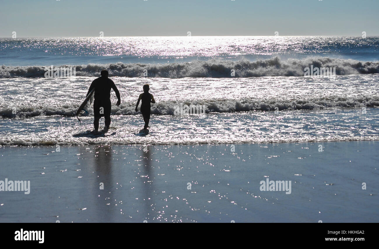 Un père et son fils de sortir pour un cours de surf de tôt le matin. Banque D'Images