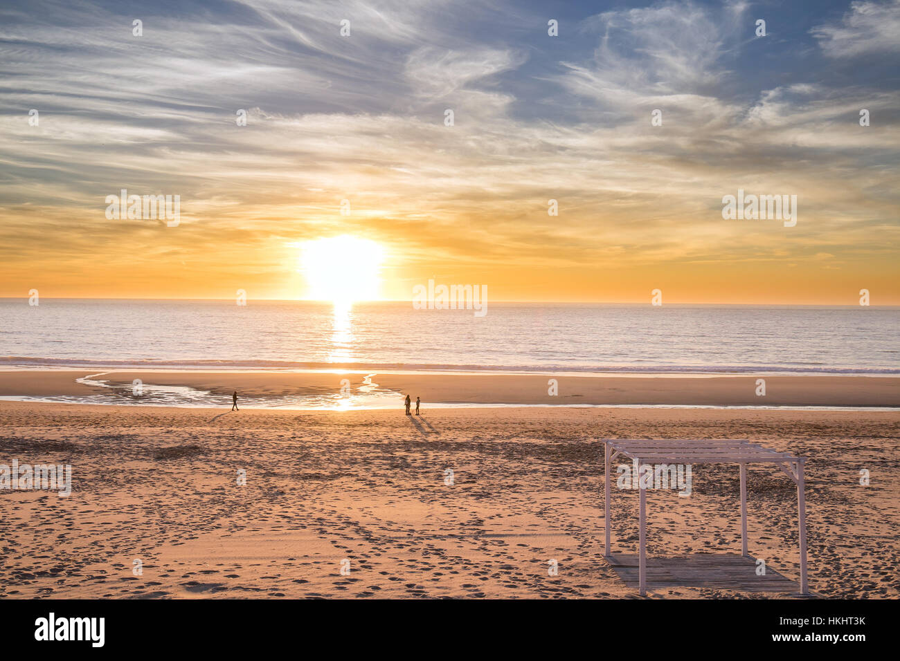 Quelques personnes marchant dans la plage pendant le coucher du soleil dans un soir d'hiver froid. Banque D'Images