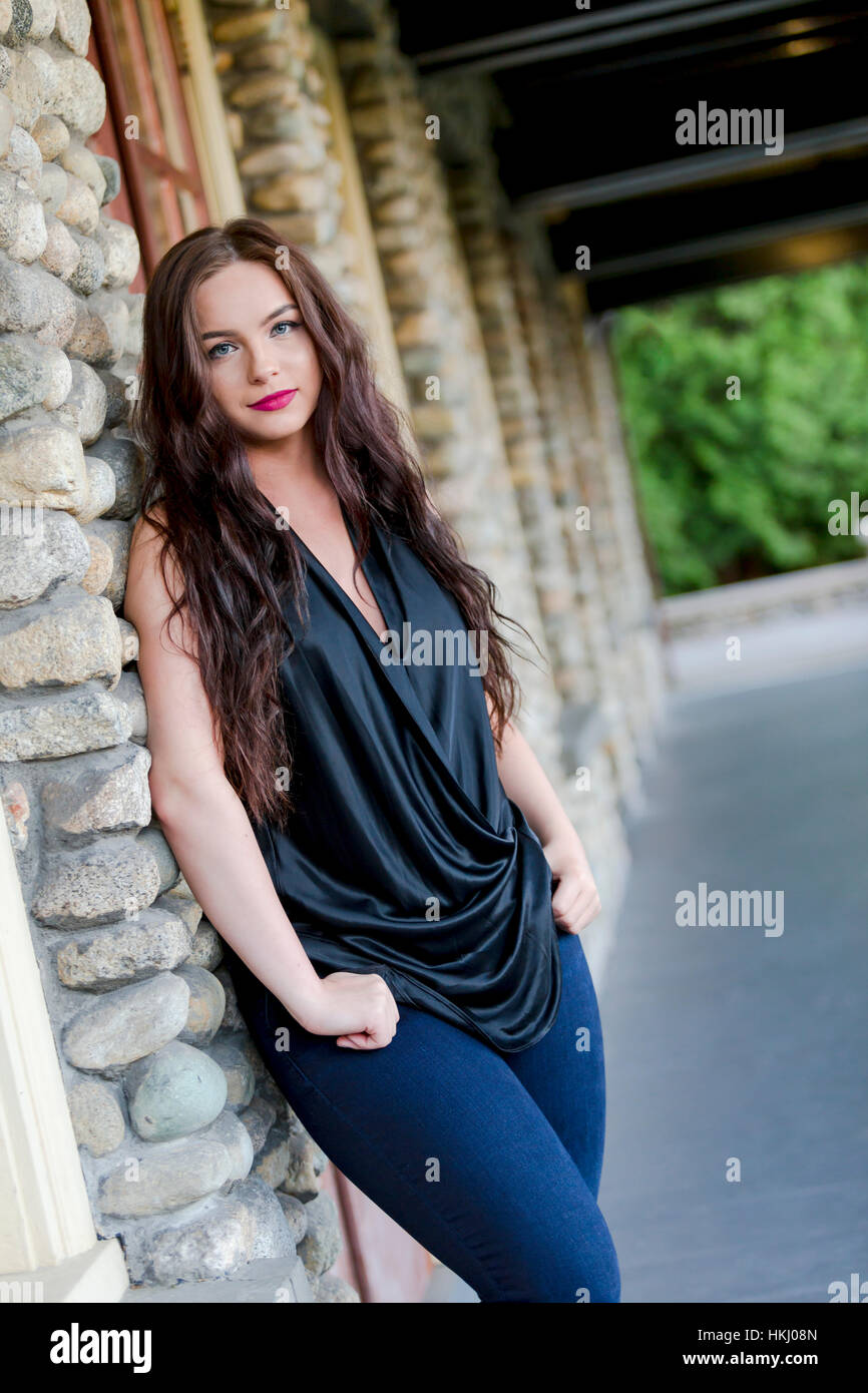 Une jeune femme dans une tenue à la mode millénaire sort de désinvolture à l'extérieur d'un restaurant de se pencher dans le mur Banque D'Images