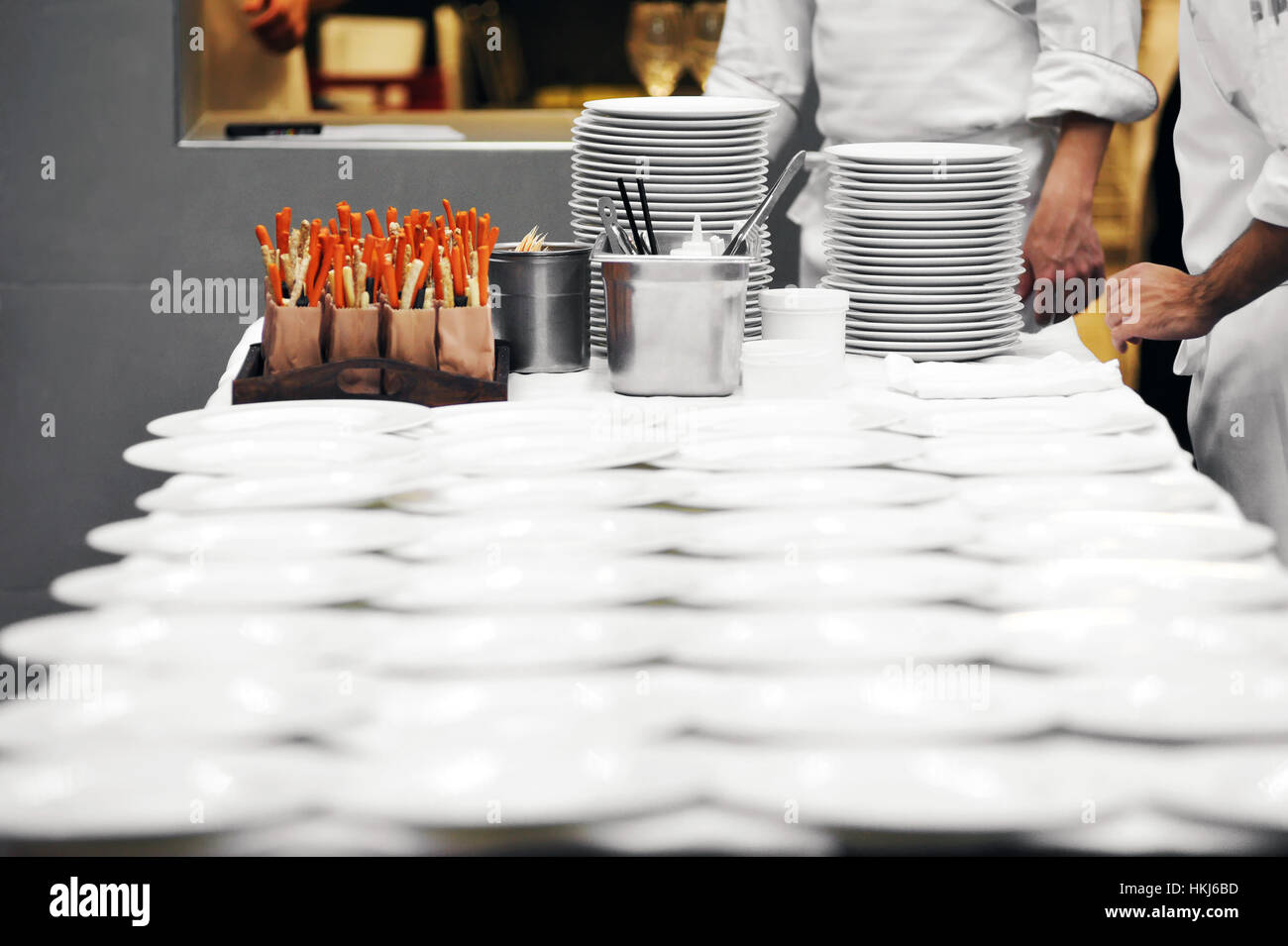 Vue latérale du chef de table dans un restaurant et les gens incognito dans les aires de préparation de plaques blanches et d'autres couverts dans le Banque D'Images