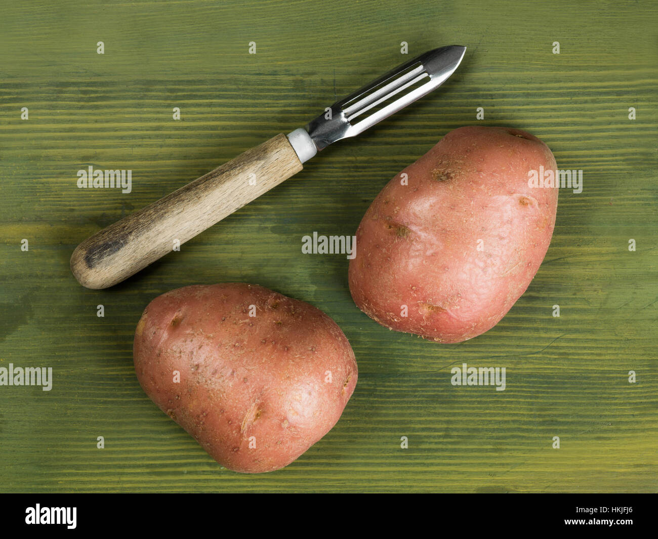 Éplucheuse de pommes de terre traditionnelles avec deux pommes de terre non cuites Banque D'Images