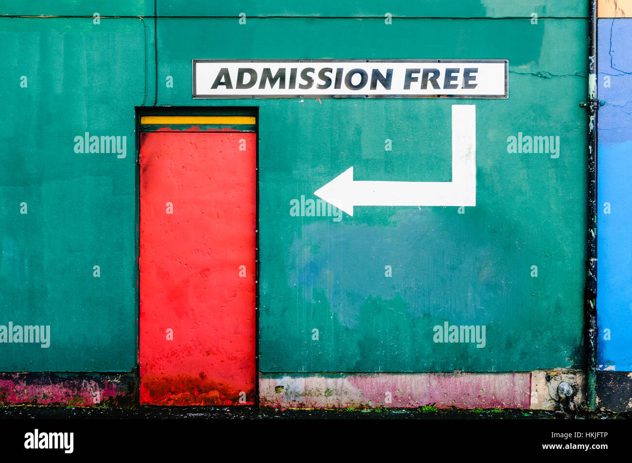 La porte rouge sur un mur vert avec un panneau disant 'Entrée libre' Banque D'Images