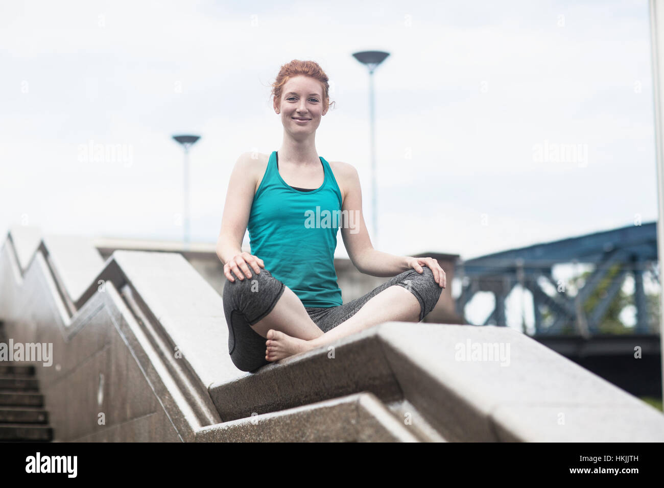 Young woman doing yoga sur mur en milieu urbain, la ville de Freiburg im Breisgau, Bade-Wurtemberg, Allemagne Banque D'Images