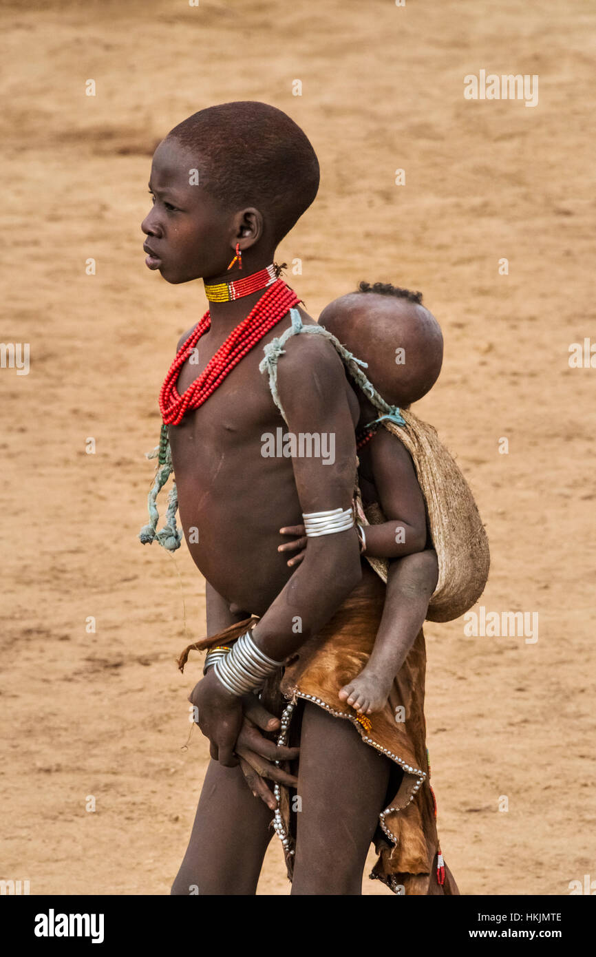 Tribu Hamar girl carrying baby à l'arrière, Hamar, village du sud Omo, Ethiopie Banque D'Images