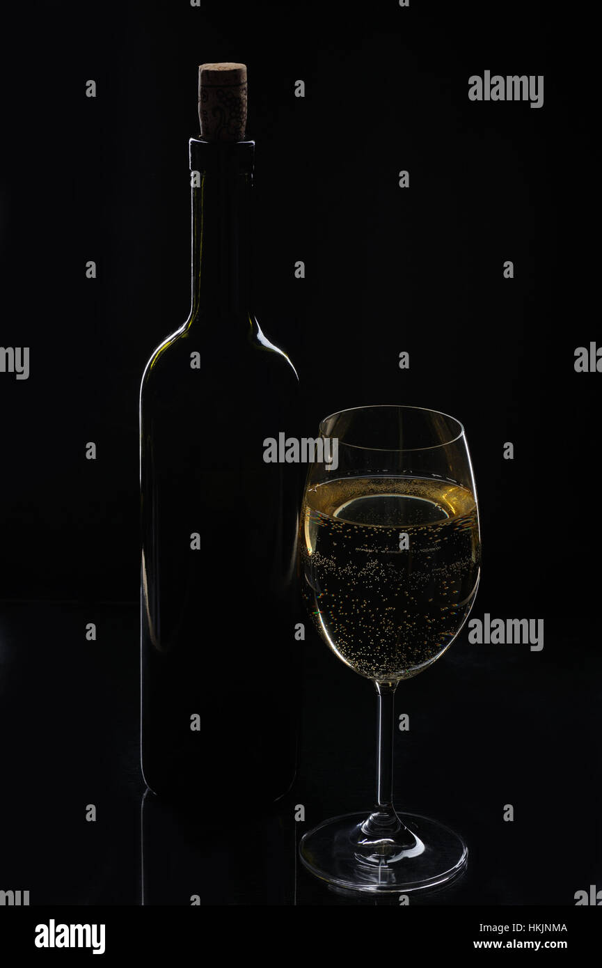 Verre à vin blanc avec bouteille sur fond noir Banque D'Images