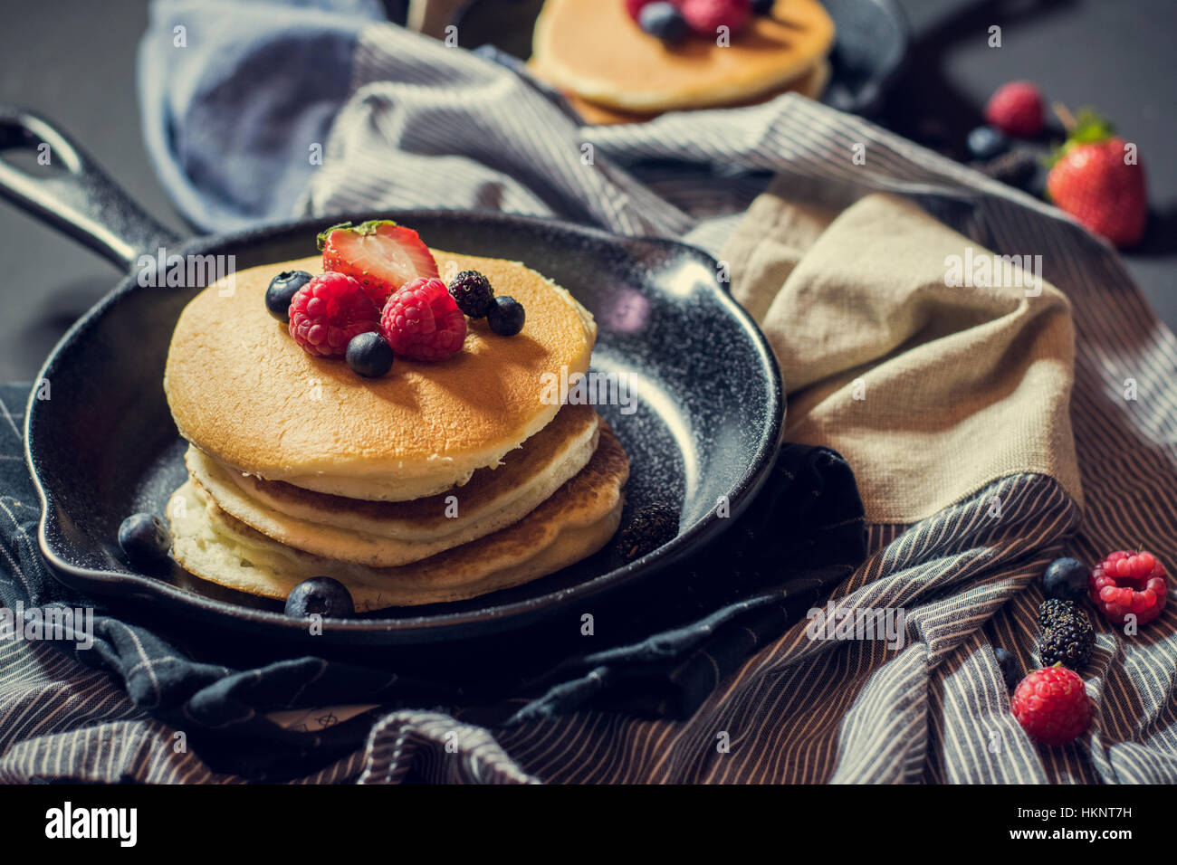 Des crêpes faites maison aux fruits rouges sur métal poêle décoré de petits fruits (bleuets, framboises et mûres). Vue d'en haut. Banque D'Images