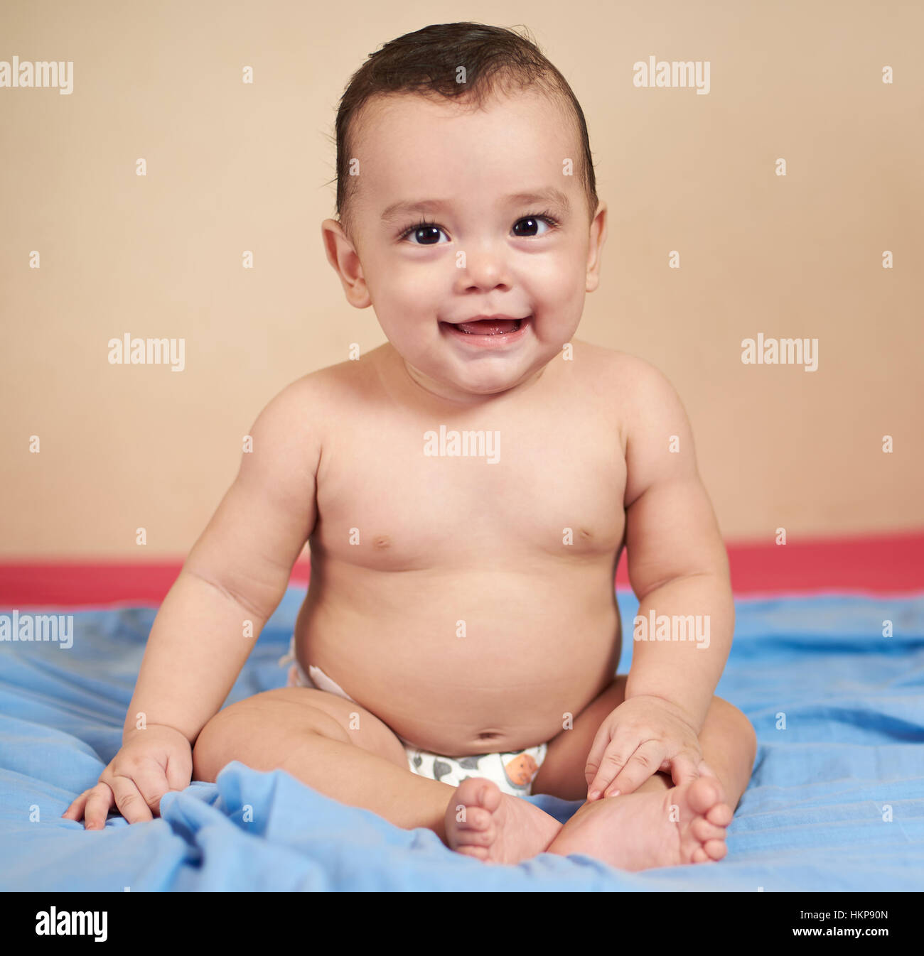 Petit smiling little baby sitting sur couverture de lit bleu Banque D'Images