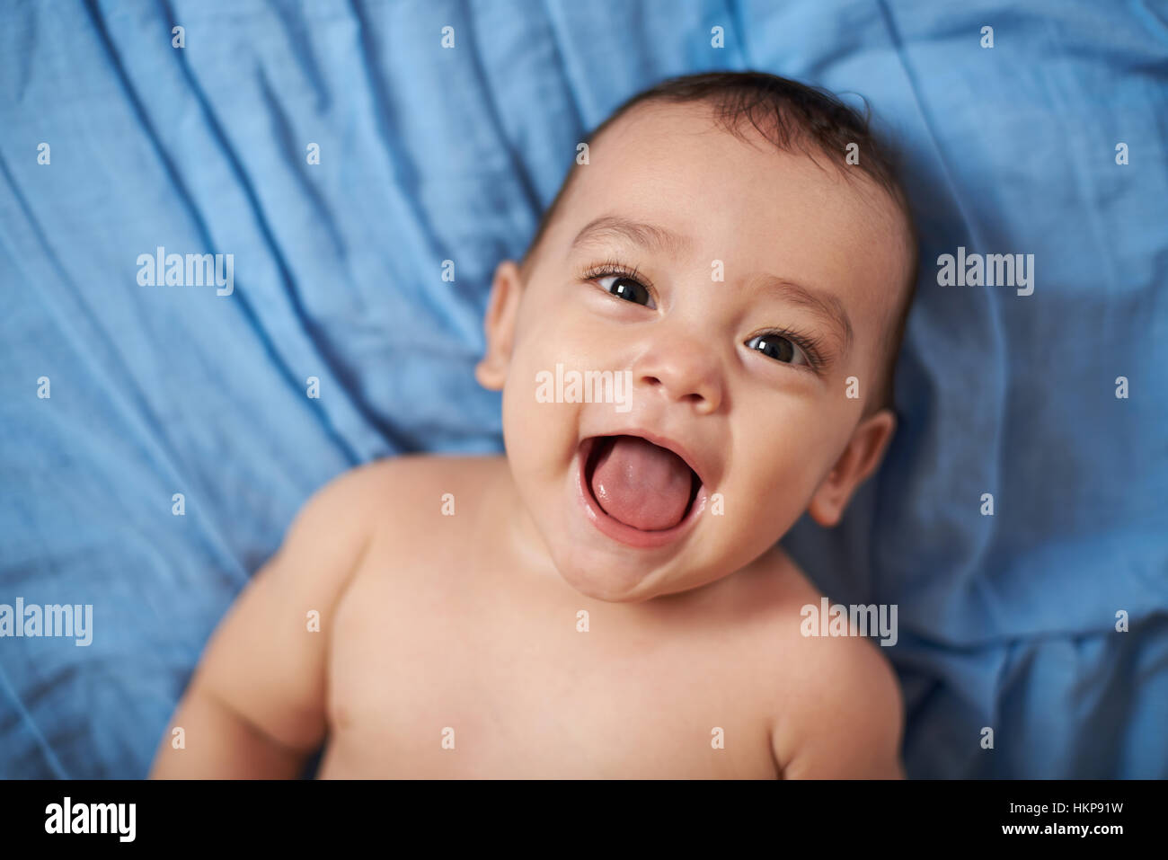 Portrait de bébé avec bouche ouverte portant sur lit couverture bleue Banque D'Images