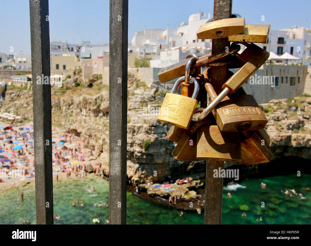 Cadenas ou serrures de l'amour à la chaîne pour les Garde-corps avec plage et soleil derrière à Polignano a Mare Italie Pouilles Banque D'Images