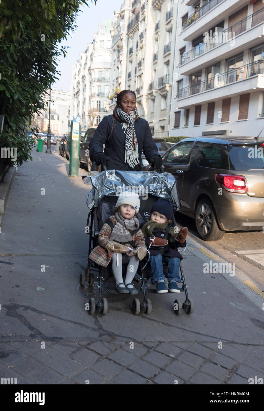 Garde noire avec deux enfants blancs dans la poussette, Auteuil, Paris, France. Banque D'Images