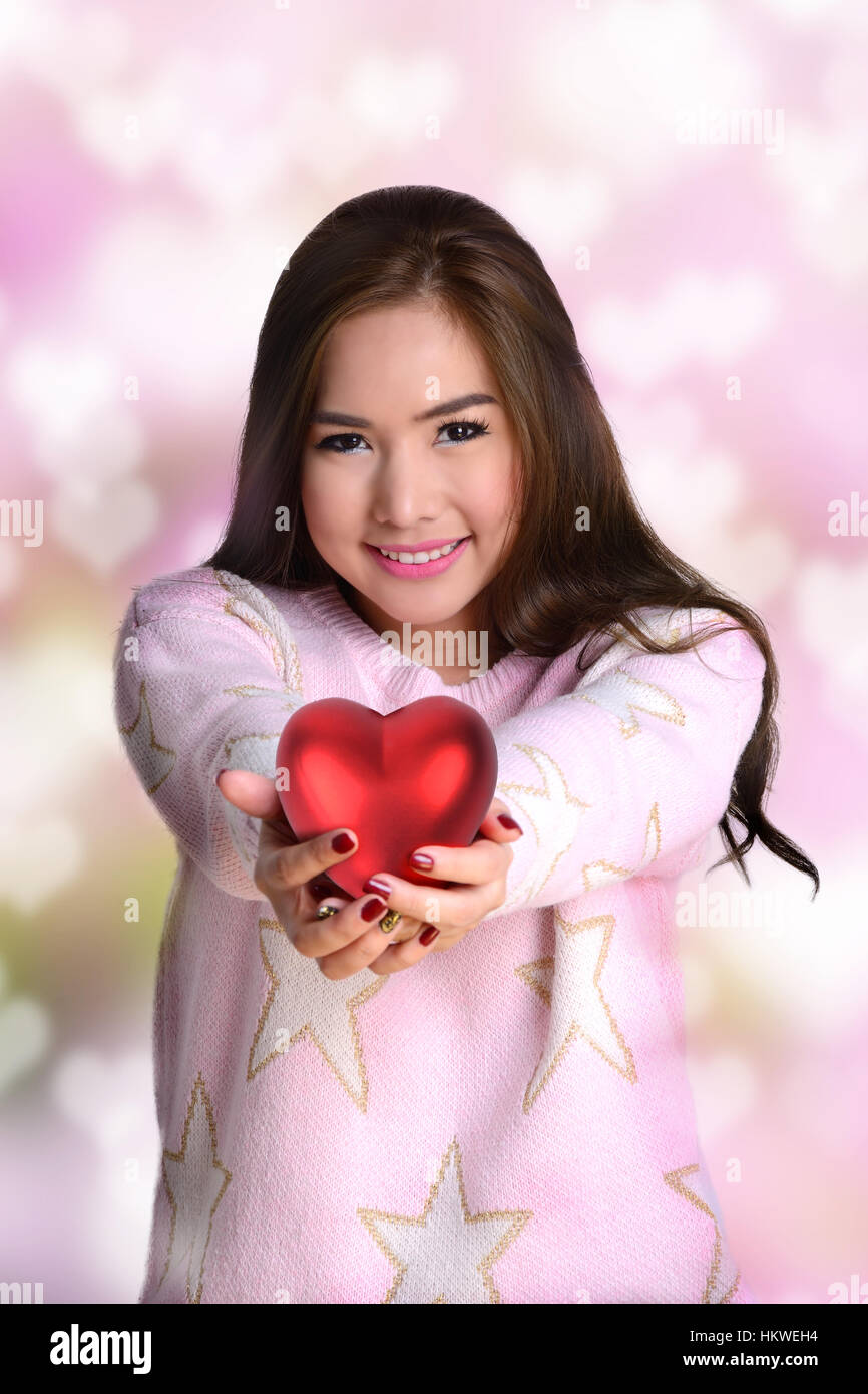 Smiley girl holding big red heart en deux mains donner à quelqu'un. Banque D'Images