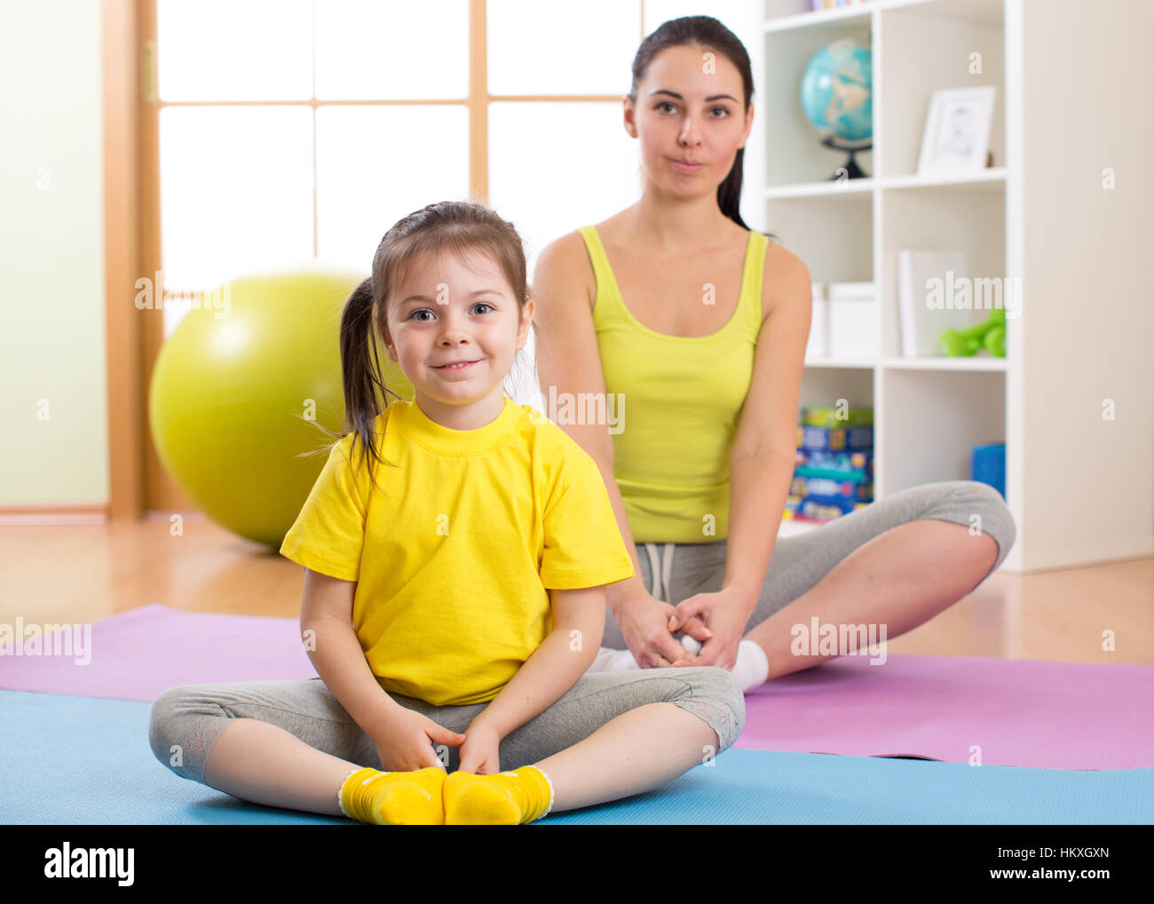 Mère et enfant fille faisant du yoga à la maison Banque D'Images