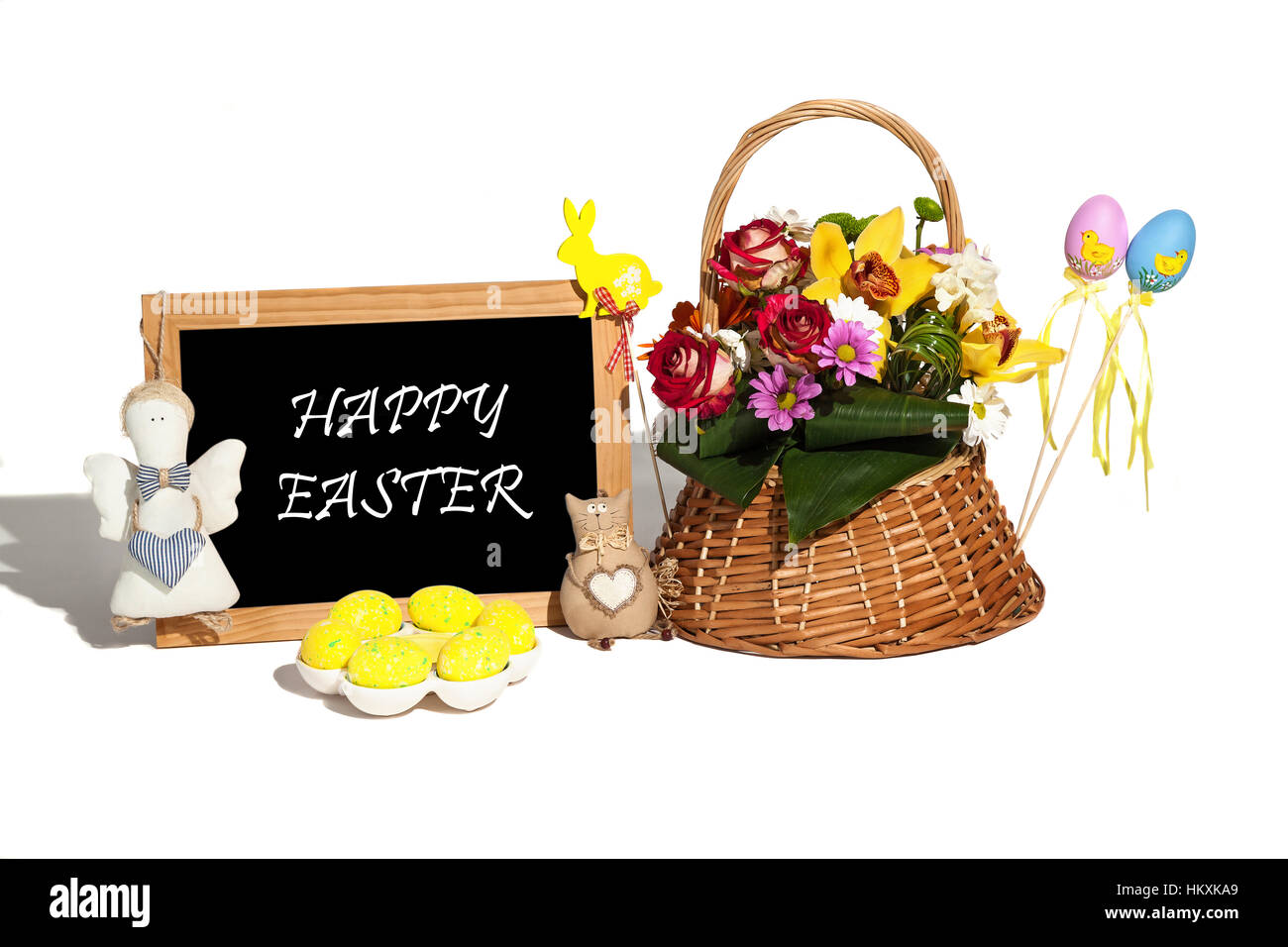 Composition de Pâques. Composition des oeufs de Pâques, le cadre photo, les jouets faits à la main et des fleurs dans un panier sur le fond blanc. Banque D'Images