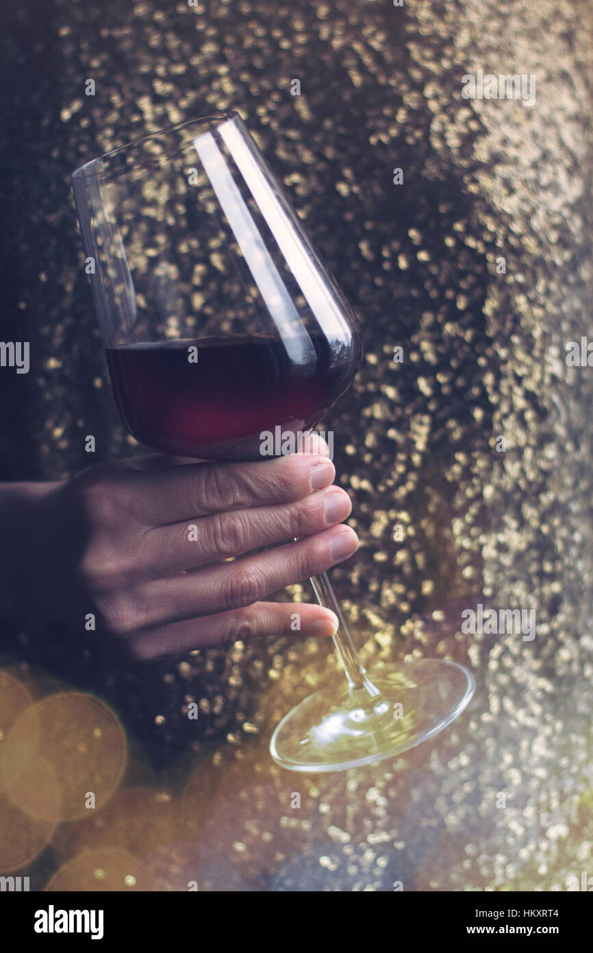 Close up of Caucasian horizontale femme retro vintage robe sequin d'or tenant un grand verre de vin rouge à l'occasion d'une fête Banque D'Images