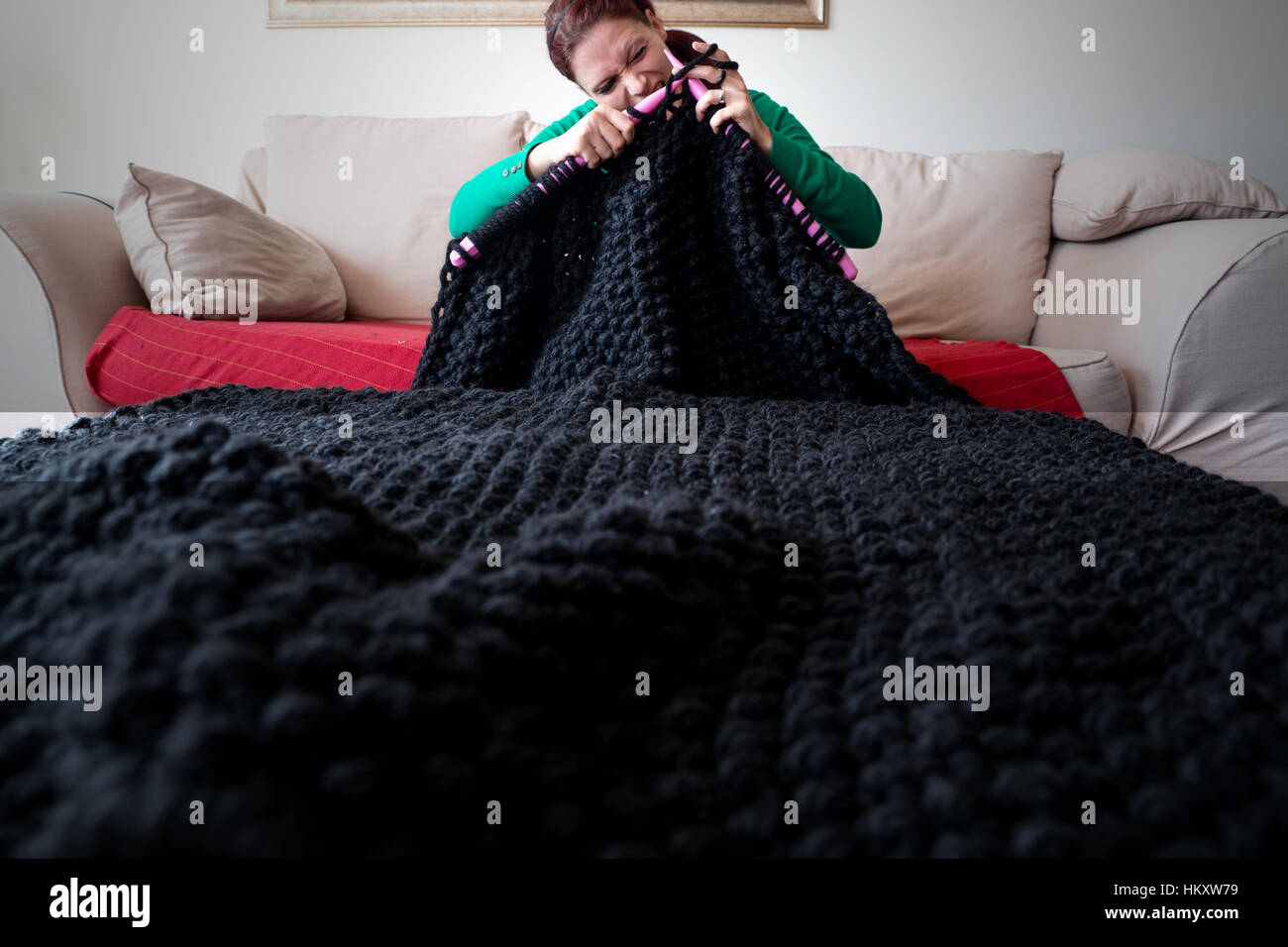 Woman knitting une couverture avec de grandes aiguilles à tricoter Banque D'Images