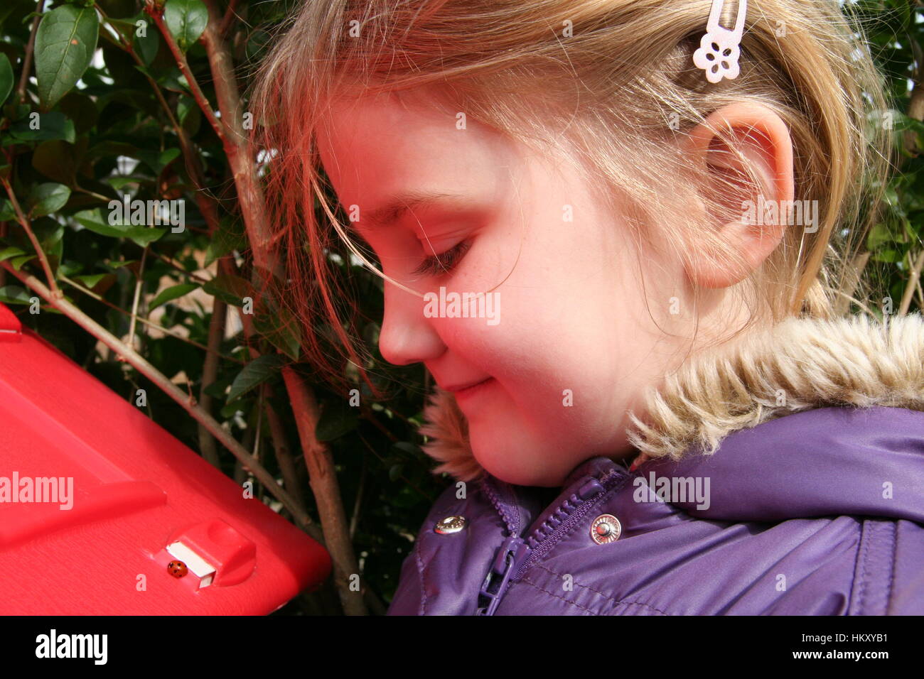 Petite fille blonde enfant qui étudie les points noirs Coccinelle rouge vif de l'été, l'awe me demande, l'exploration de l'enquête, à la curieuse conception inquisitiv Banque D'Images