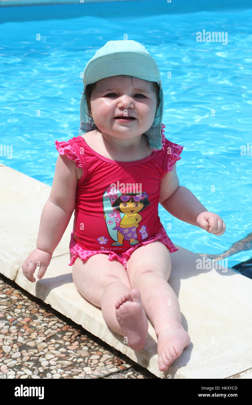 Enfant Bébé fille s'asseoir près de la piscine le port d'un chapeau /  chapeau et de natation maillot de bain, bébé, famille amour concept amusant  Photo Stock - Alamy