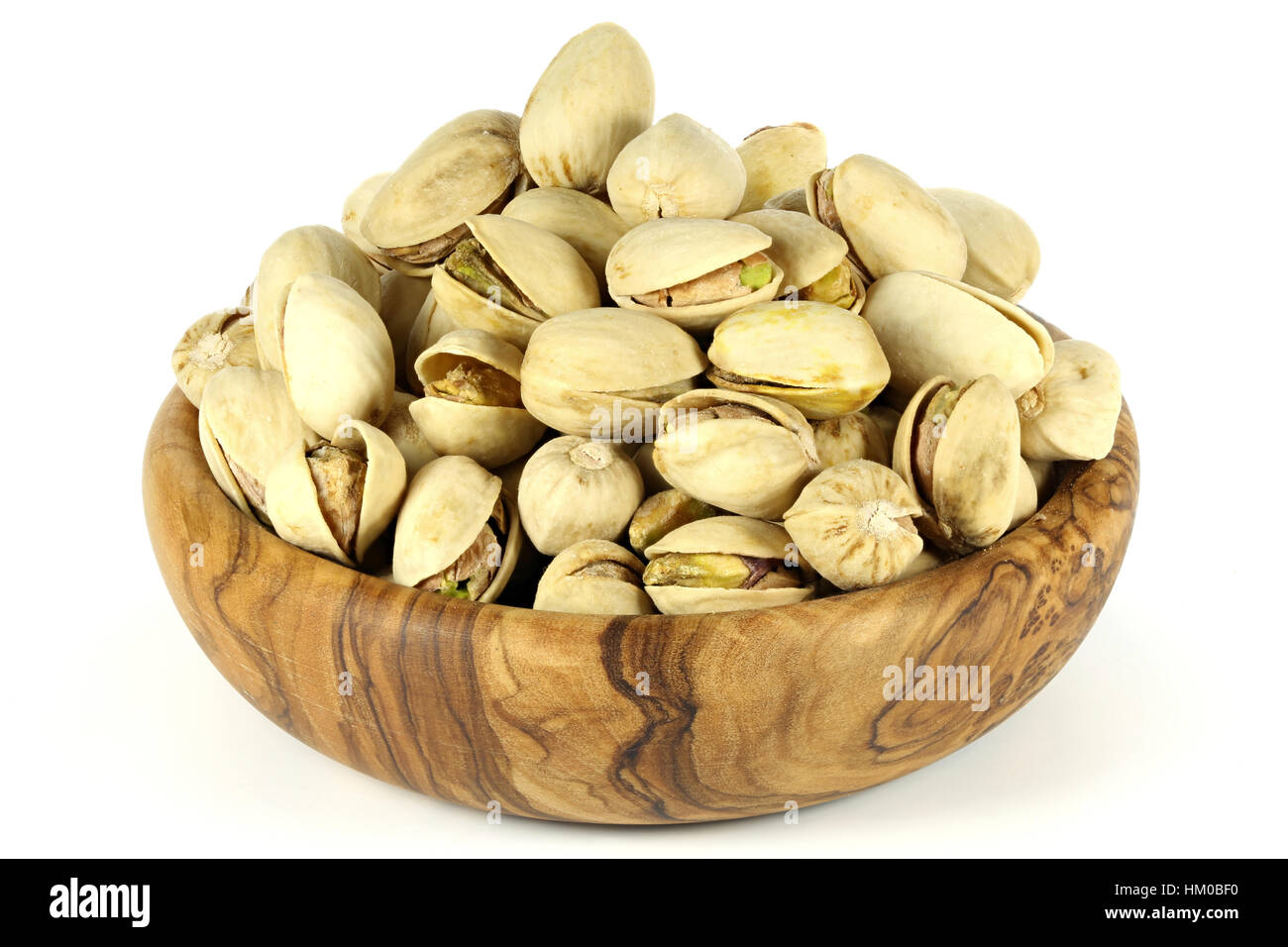 Les pistaches dans un bol en bois d'olive isolé sur fond blanc Banque D'Images