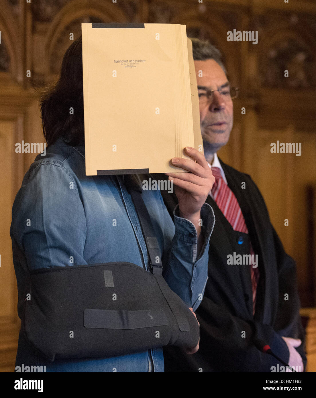 Brême, Allemagne. Jan 31, 2017. Le défendeur dans un procès pour meurtre (L) cache son visage derrière un dossier dans la salle d'audience de la cour régionale de Brême, Allemagne, 31 janvier 2017. Le défendeur, un motorbiker et Youtube-filmer, est accusé d'avoir renversé et mortellement blessé un 75-year-old piétons en juin 2016. Il a régulièrement tourné son tour en moto avec un casque appareil photo et vidéos téléchargées sur youtube. Photo : Ingo Wagner/dpa/Alamy Live News Banque D'Images