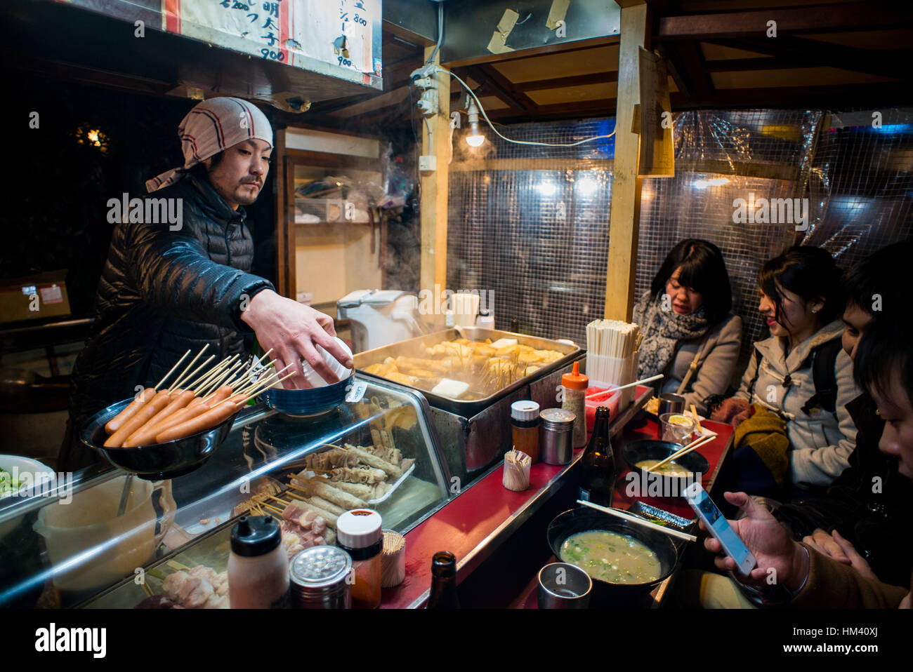 Un cuisinier, divertit et se prépare à un groupe de convives dans un des célèbres Fukuoka chariots yatai Banque D'Images