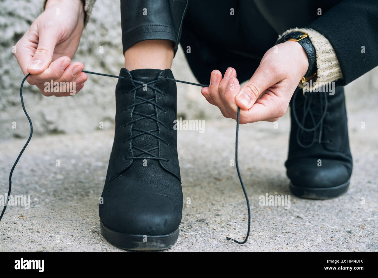 Femme en vêtements élégants attacher ses lacets de chaussures de près. Lacets de délié au cours d'une balade dans la ville Banque D'Images
