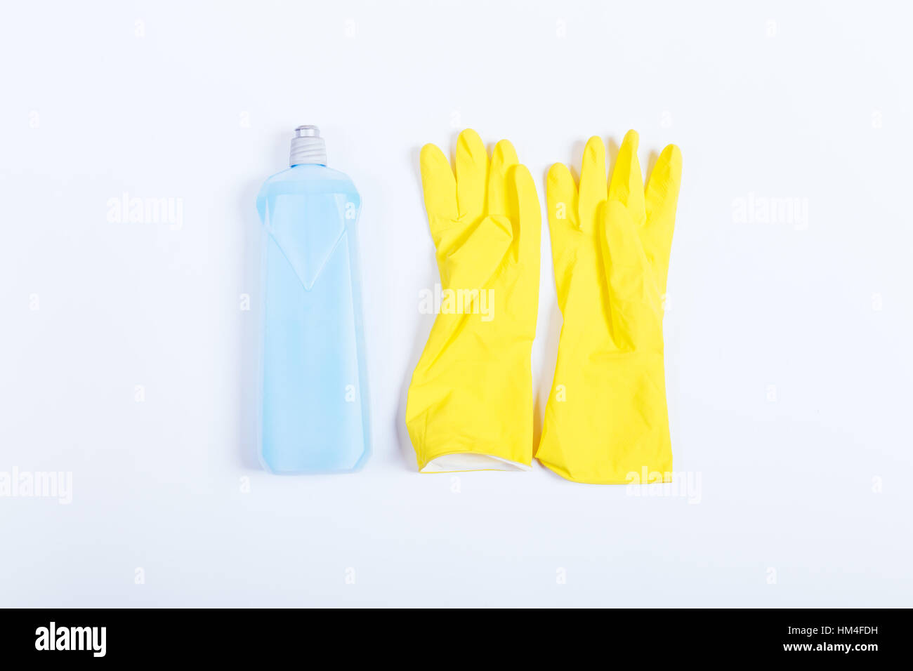 Gants en caoutchouc jaune et bleu une bouteille de détergent sur fond blanc, vue du dessus Banque D'Images