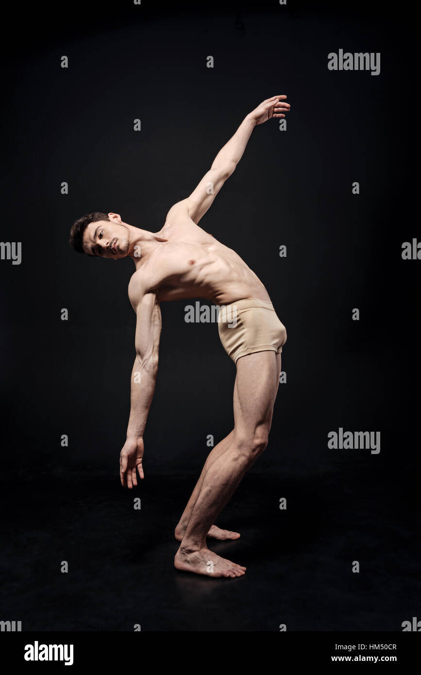 Peaceful young gymnast dans le noir studio lumineux Banque D'Images