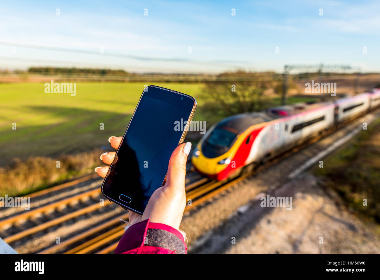 La vue quotidienne de woman holding smartphone plus UK Railroad Banque D'Images