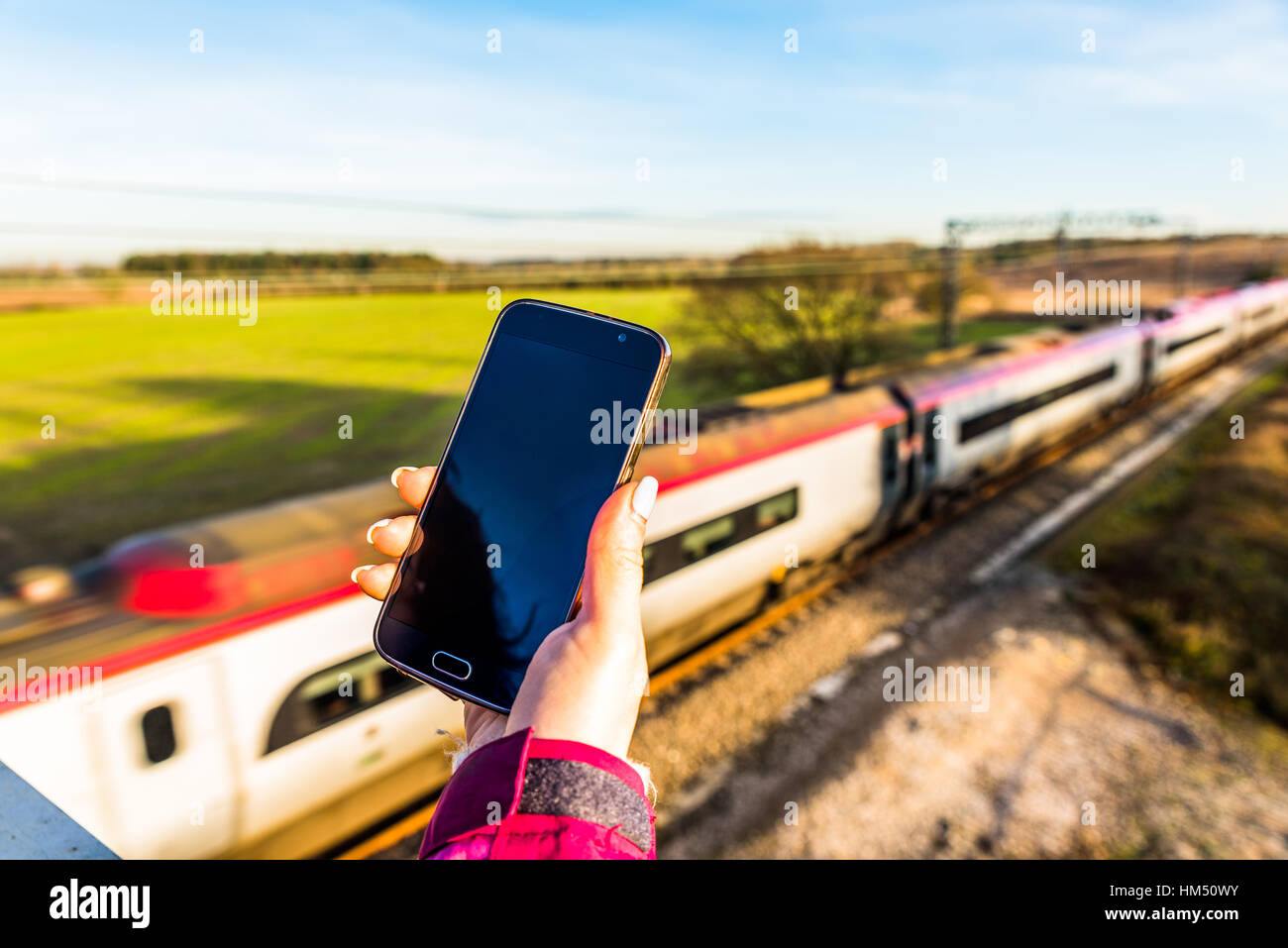 La vue quotidienne de woman holding smartphone plus UK Railroad Banque D'Images