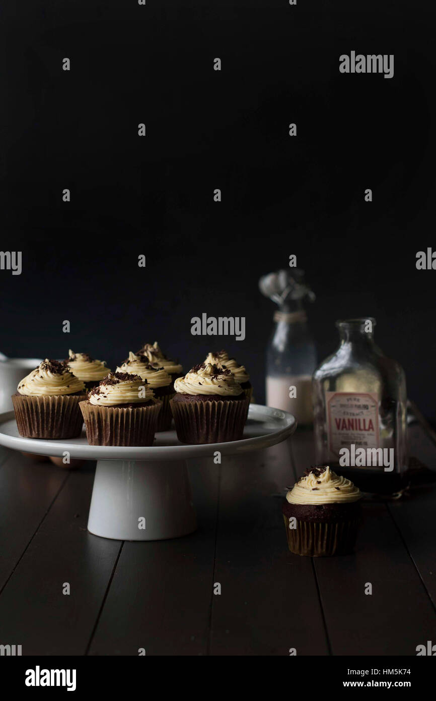 Cupcakes en cakestand avec des bouteilles sur le tableau sur fond noir Banque D'Images