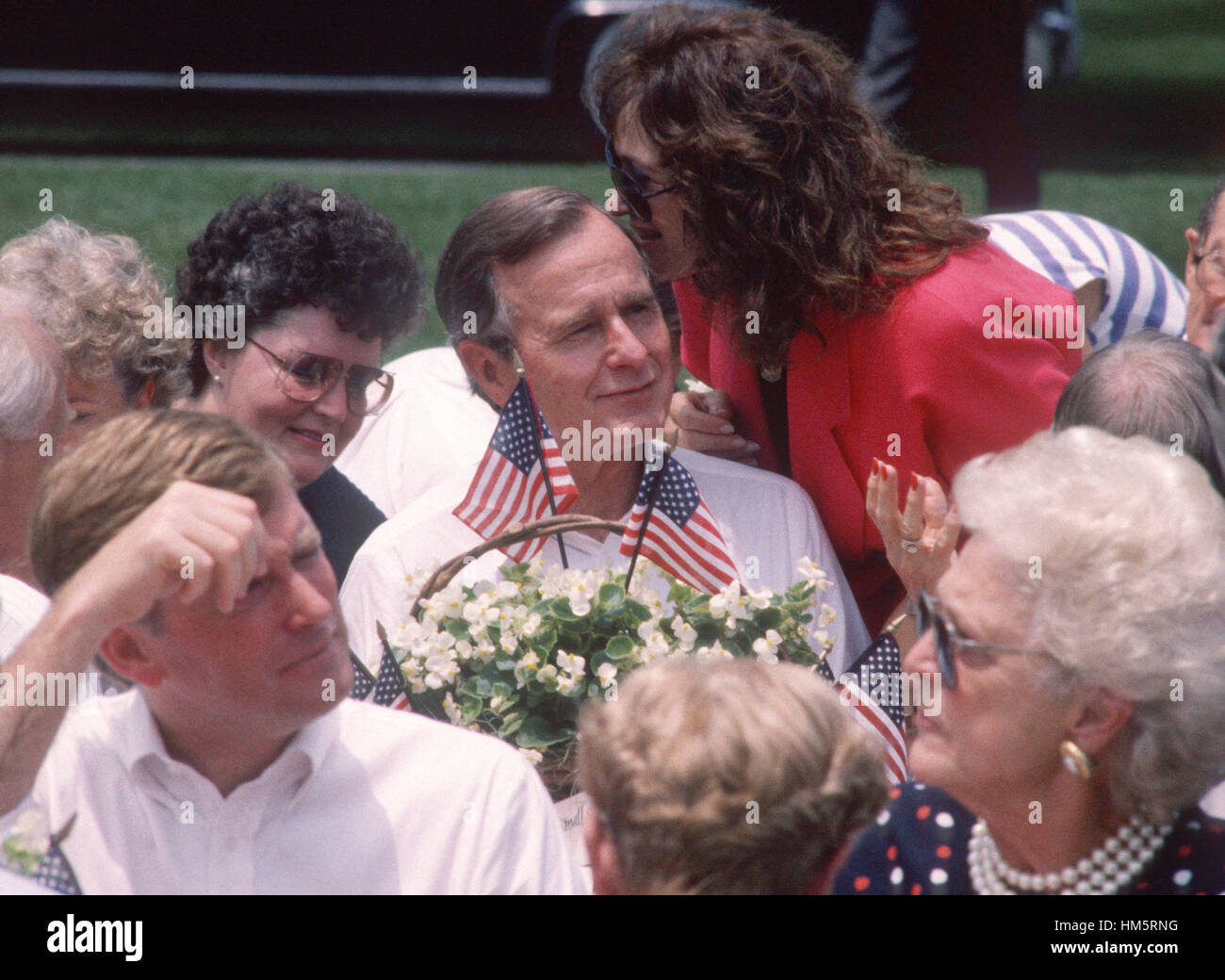 Le président des États-Unis George H. W. Bush à l'écoute d'une femme non identifiée au cours d'un barbecue sur la pelouse Sud de la Maison Blanche à Washington, D.C. pour commémorer le 20e anniversaire de l'alunissage d'Apollo 11 le 20 juillet 1989. Visible dans l'foregro Banque D'Images