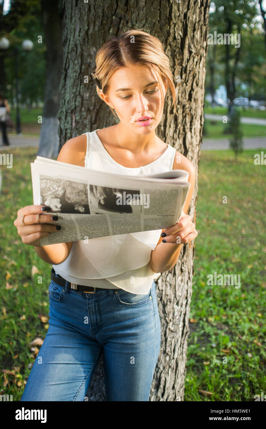 Gorgeous woman reading a magazine dans le parc Banque D'Images