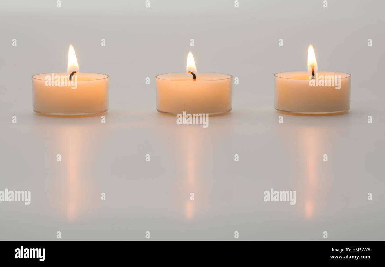 Trois bougies blanches sur un fond blanc. Banque D'Images