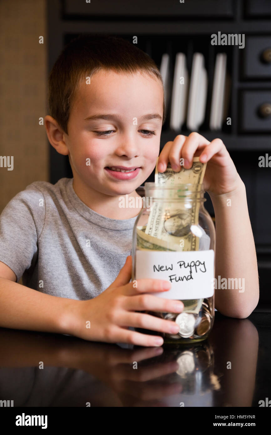 Smiling boy (6-7) d'engloutir des fonds pour acheter chiot Banque D'Images